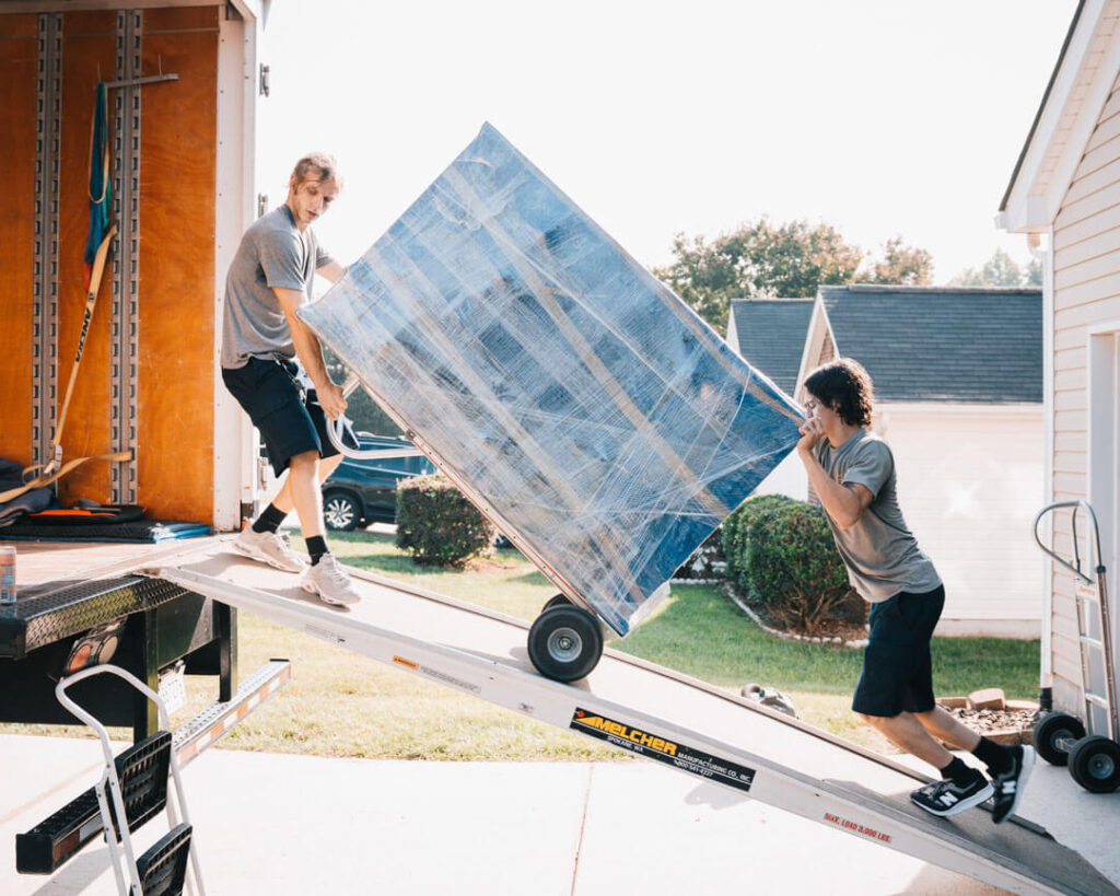 Two men carefully loading a moving truck