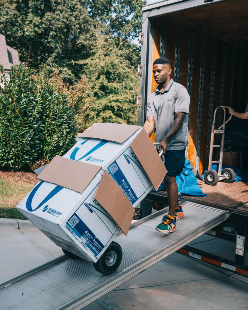 A man unloading boxes from a truck with a dolly